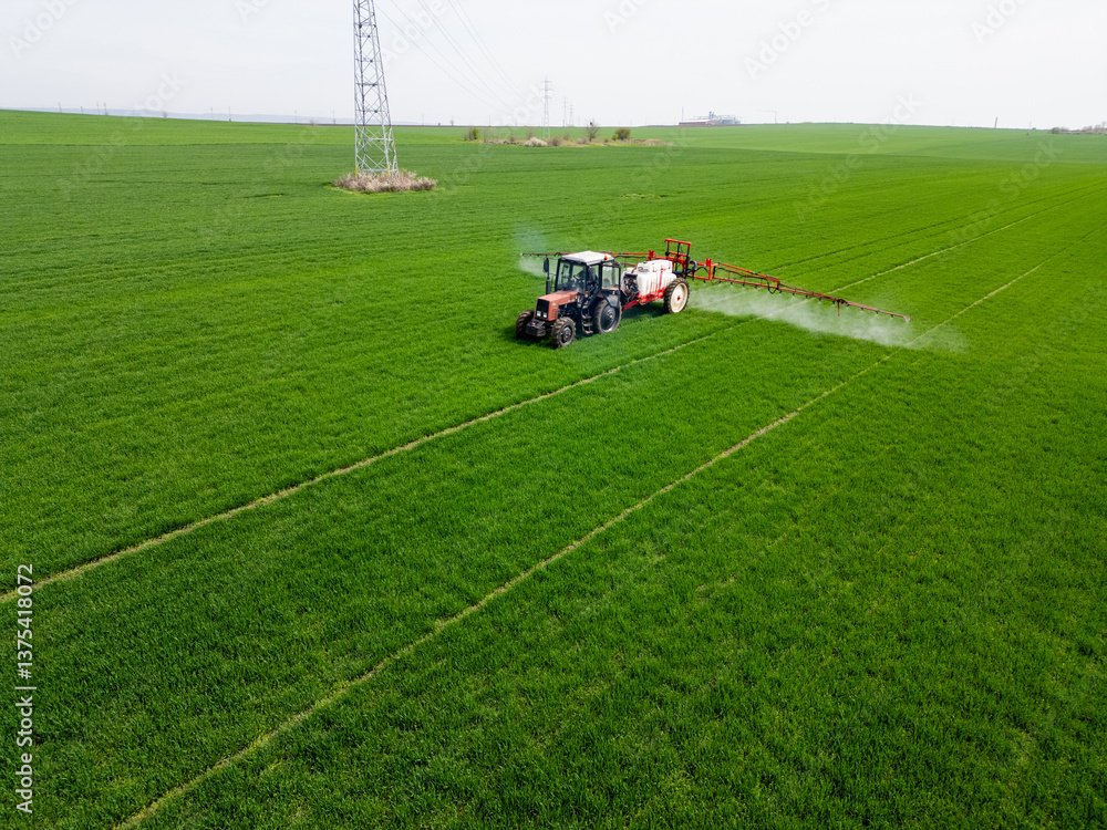 Tractor spraying fertilizer or pesticide on a large green field during spring, demonstrating modern agricultural technology and crop care Tractor spraying fertilizer or pesticide on a large green field during spring, demonstrating modern agricultural technology and crop care