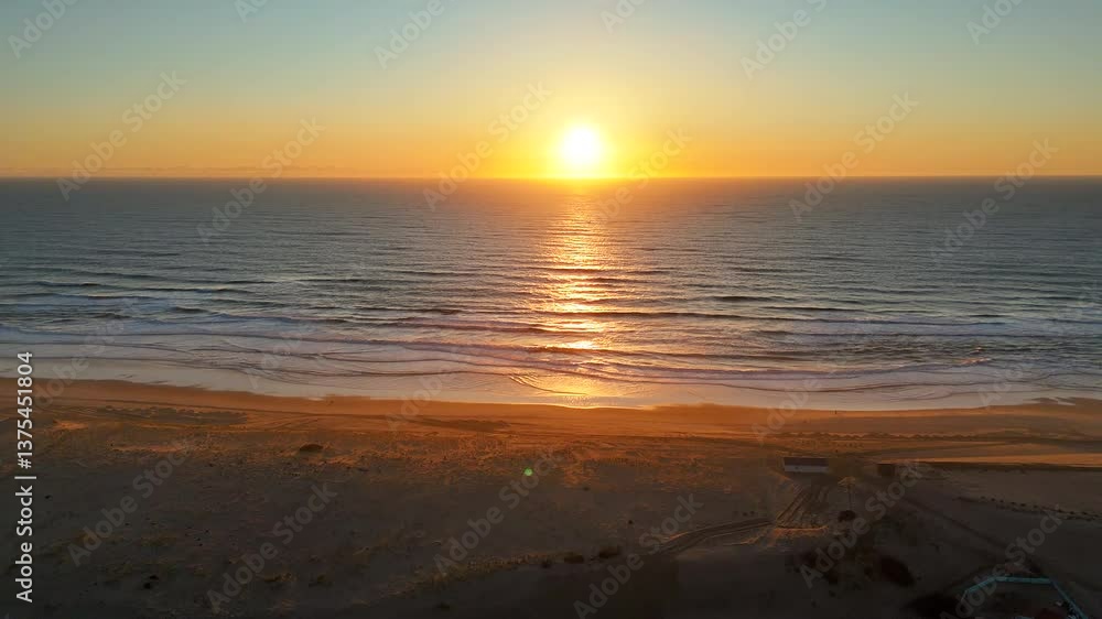 Aerial drone view of coastal village Loncau at golden sunset, showing glowing ocean horizon, soft waves, and peaceful beach bathed in warm evening light. Ideal for travel or editorial use. Aerial drone view of coastal village Loncau at golden sunset, showing glowing ocean horizon, soft waves, and peaceful beach bathed in warm evening light. Ideal for travel or editorial use.