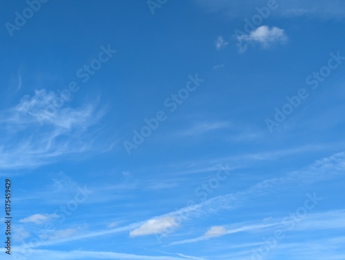 Blue Skies with wispy chemtrail aeroplane lines and fluffy white clouds