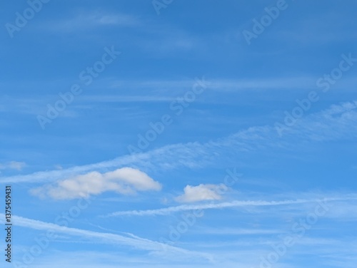 Blue Skies with wispy chemtrail aeroplane lines and fluffy white clouds