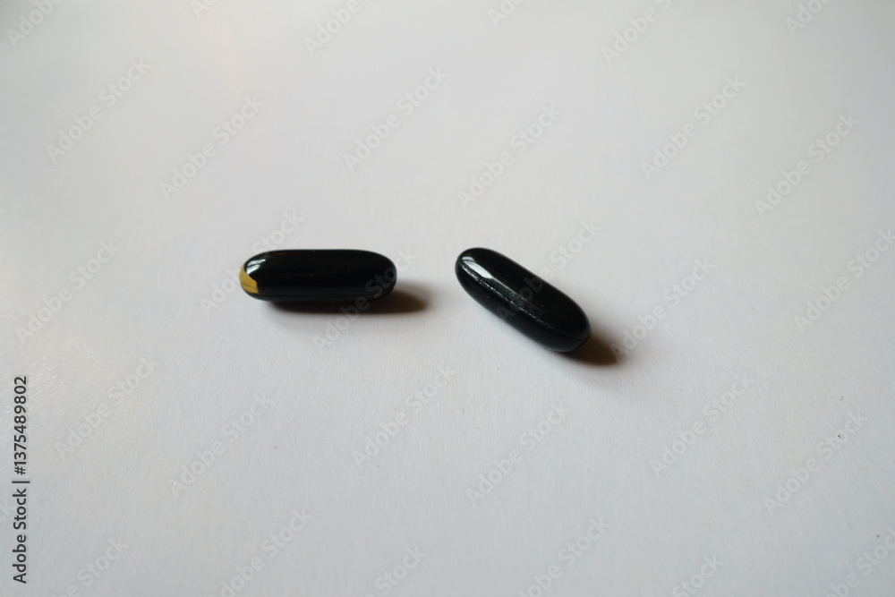 Pair of black softgel capsules of activated charcoal