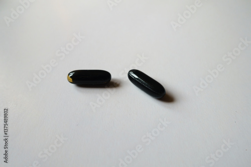 Obraz na płótnie Pair of black softgel capsules of activated charcoal w salonie
