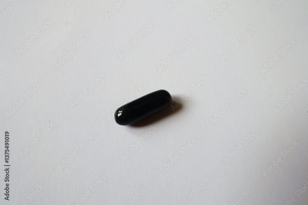 Close shot of one black softgel capsule of activated charcoal