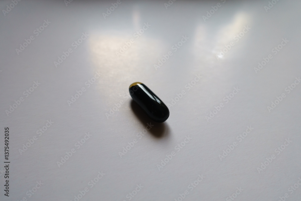 Macro of one black softgel capsule of activated charcoal