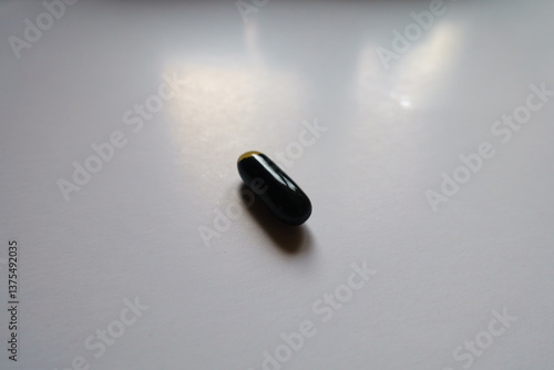 Obraz na płótnie Macro of one black softgel capsule of activated charcoal w salonie