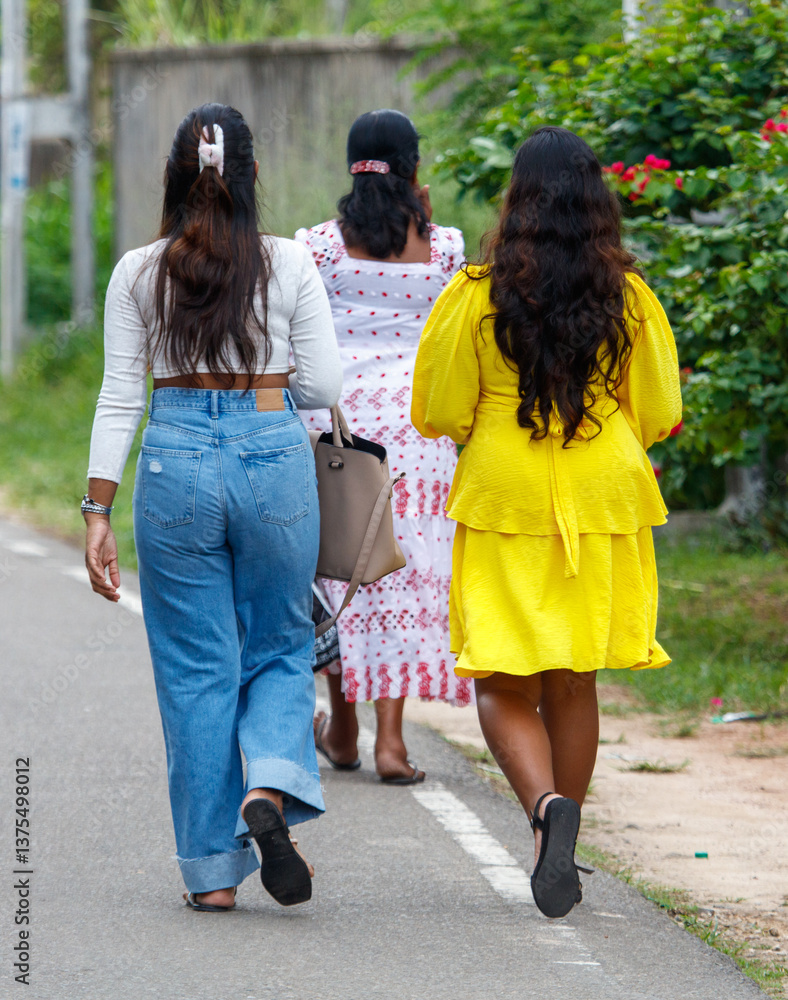 Obraz premium Three women walking down a street, one wearing a yellow dress