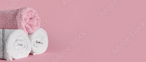 Rolled soft towels on pink background with space for text