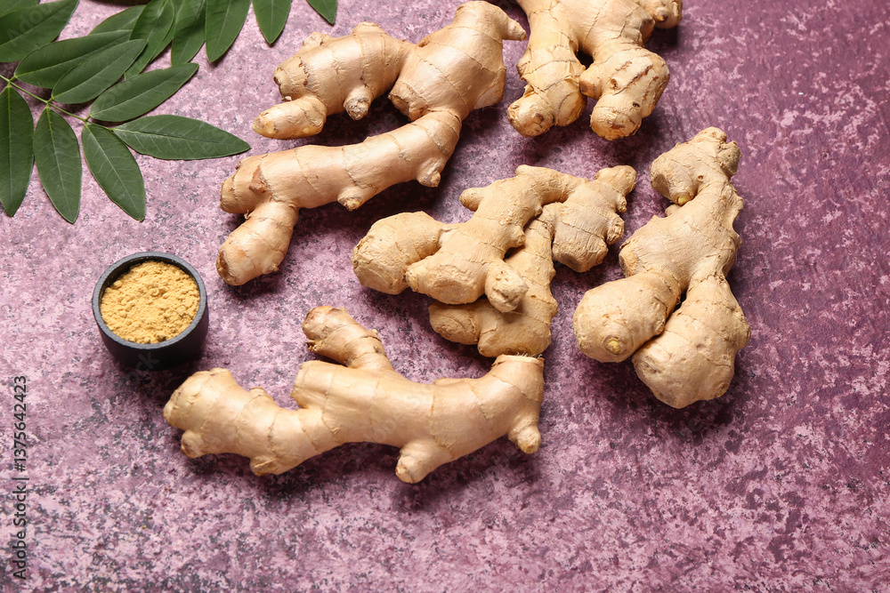 Fototapeta premium Fresh ginger roots with leaves and bowl of dried powder on purple background