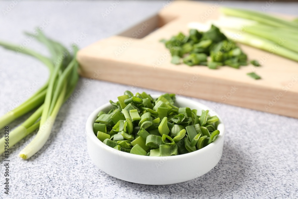 Whole and cut fresh green onions on light grey table, closeup Whole and cut fresh green onions on light grey table, closeup