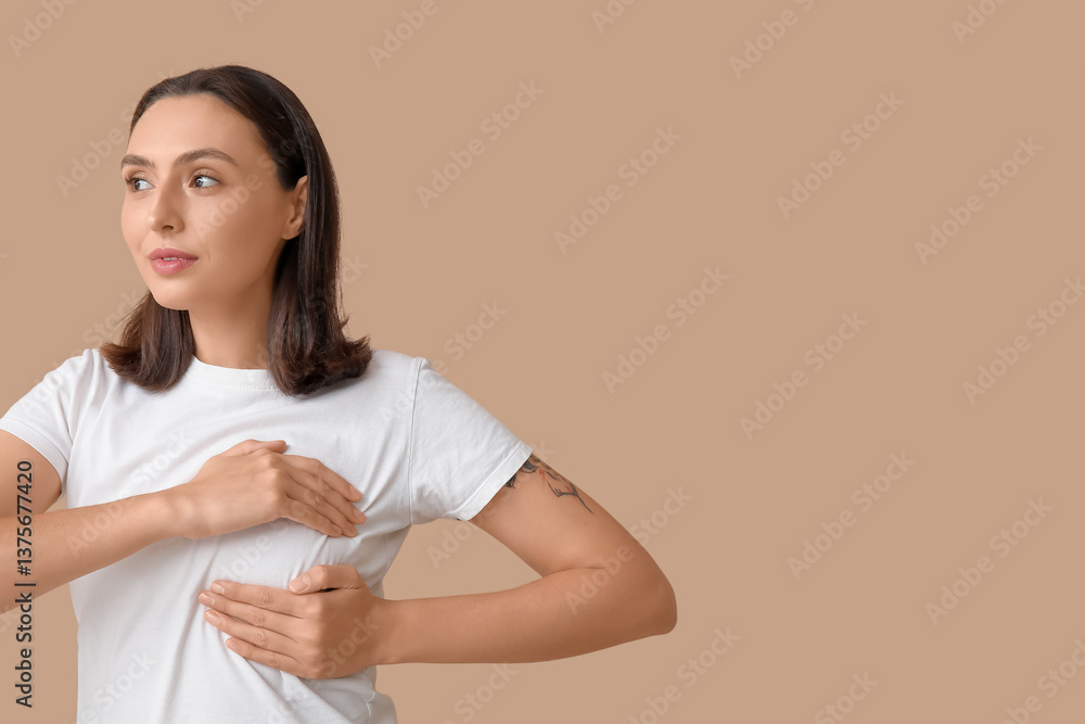 Fototapeta premium Young woman checking her breast on beige background. Cancer awareness concept