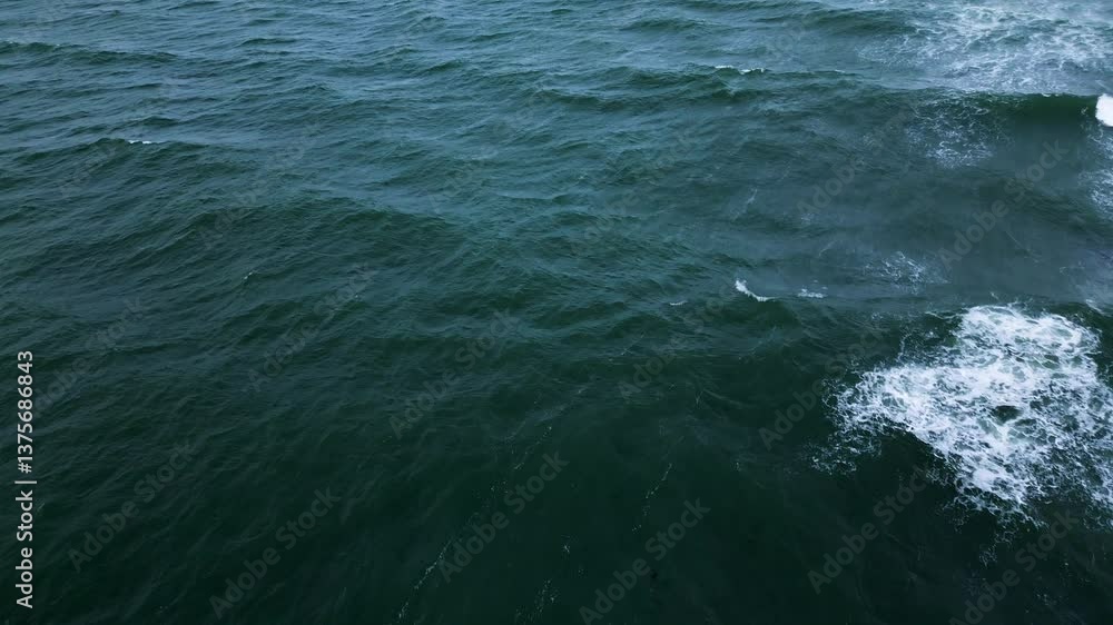 Aerial view of ocean waves crashing and creating white foam on deep green water Aerial view of ocean waves crashing and creating white foam on deep green water