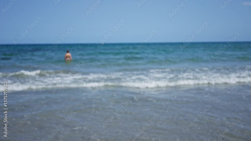 Defocused man swimming in the ocean with blurred waves and sky in the background on a sunny day Defocused man swimming in the ocean with blurred waves and sky in the background on a sunny day