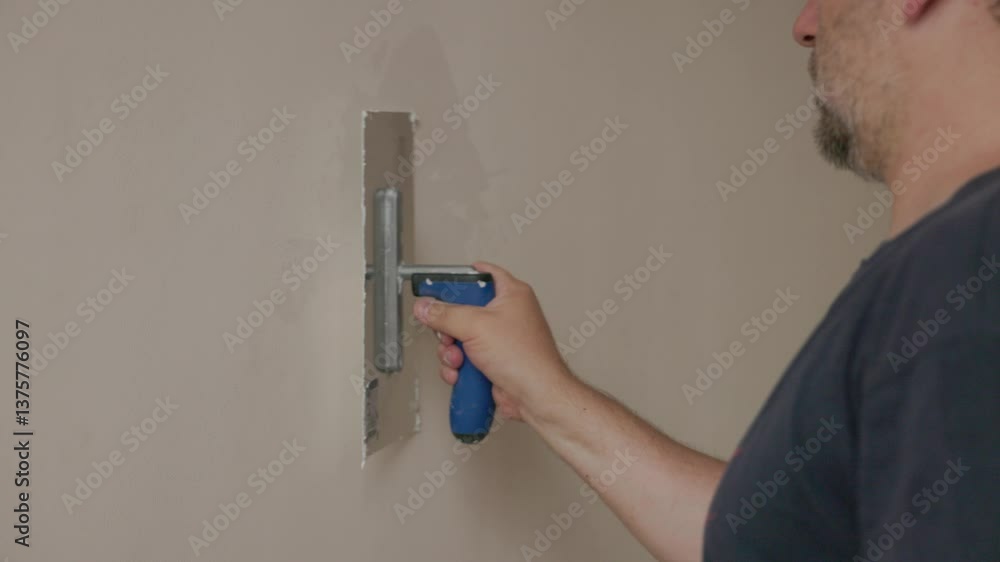 a worker applying plaster to a wall using a trowel a worker applying plaster to a wall using a trowel