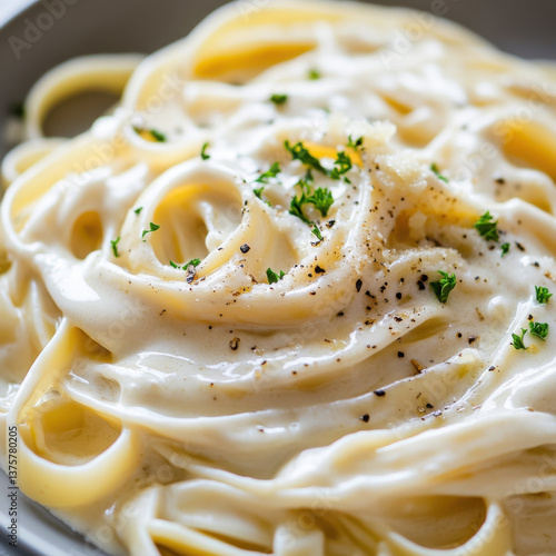 A close-up of a gourmet plate featuring creamy tagliolini pasta in a rich, velvety cream sauce infused with truffle. The pasta is elegantly 