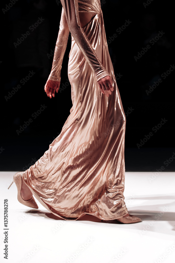 Fototapeta premium Long beige glittering dress on a female figure, stylish fashion clothing details against the black background