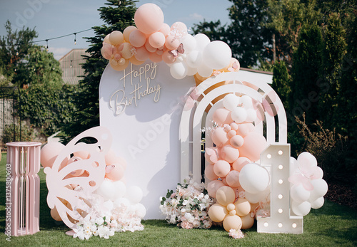 Outdoor birthday photo zone with white arch, pink balloons, and neon Happy Birthday sign