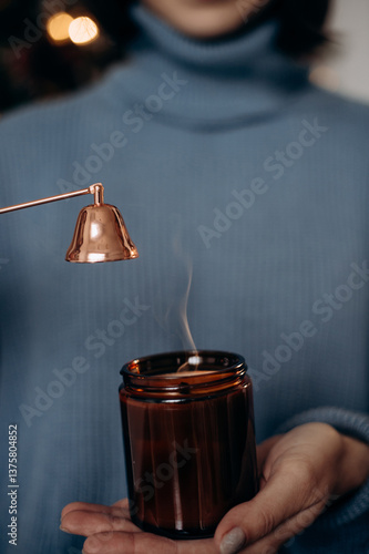 A close-up of a young woman extinguishing a candle using a candle snuffer. A serene and detailed moment capturing the candle care process