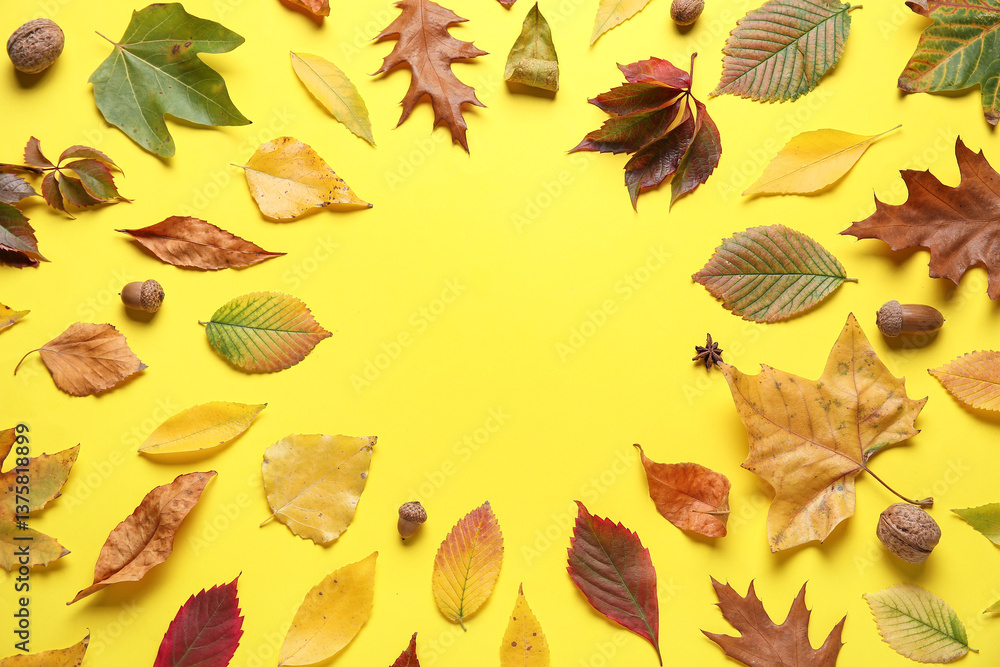 Obraz premium Frame made of beautiful fallen leaves, acorns and walnuts on yellow background