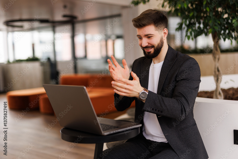 Joyful male entrepreneur applauding after achieving business success, working with laptop in modern office. Joyful male entrepreneur applauding after achieving business success, working with laptop in modern office.