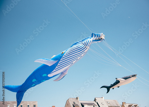 Whale-shaped kites above rooftops