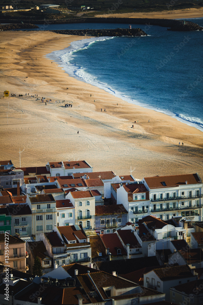 A view of the coastal houses and the beach of Nazaré, Portugal, on a beautiful day.