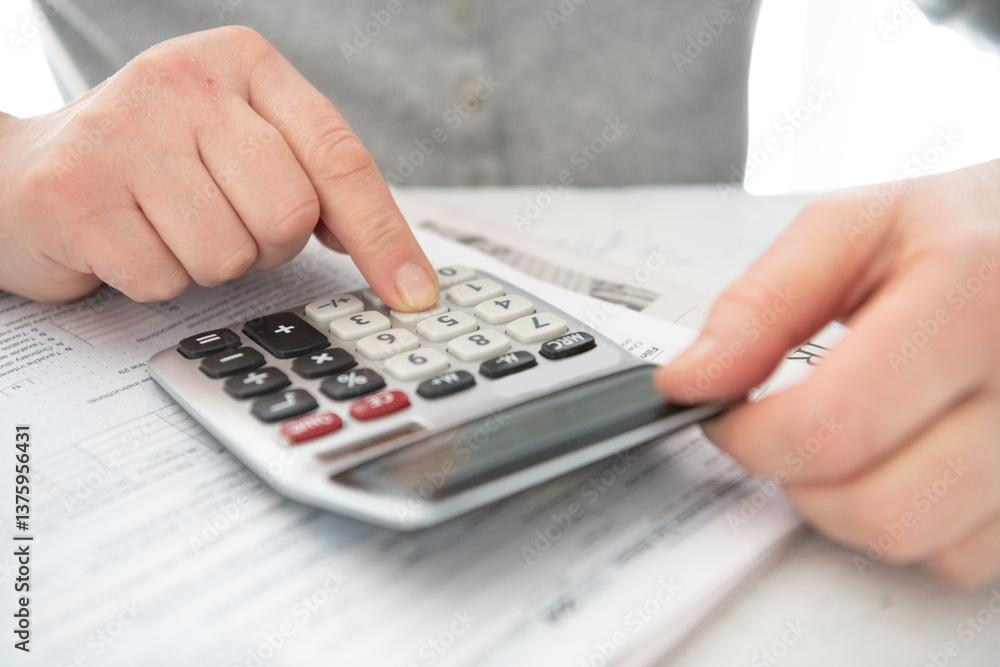 man prepares a tax report using a calculator in his home. man prepares a tax report using a calculator in his home.