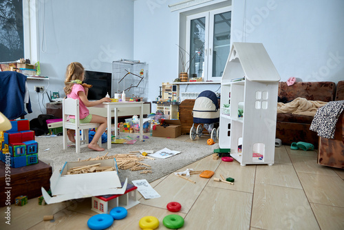 Child Playing in Messy Room Surrounded by Toys