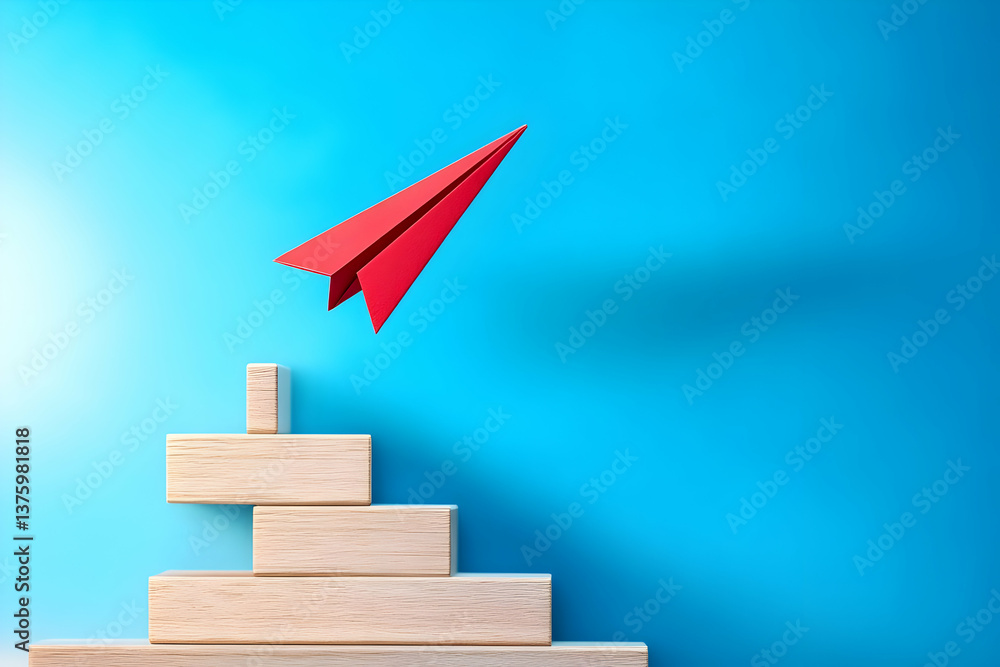 Fototapeta premium A red paper airplane is soaring above wooden blocks against a blue background, symbolizing creativity and innovation in business.