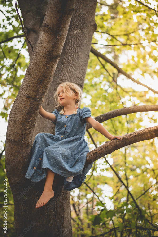 © Johnér - Low angle view of girl sitting on branch of tree in forest © Johnér - Low angle view of girl sitting on branch of tree in forest