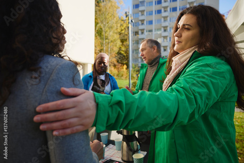 Female volunteer consoling woman with hand on shoulder at park