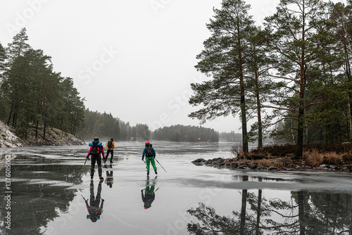 Male and female friends ice skating on frozen lake during weekend travel