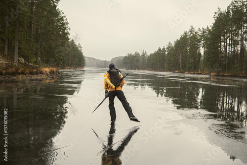 Rear view of man ice skating on frozen lake in morning