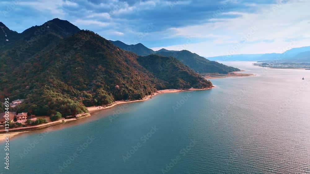 Narrow line of the sandy beach located at the foot of the mountain range covered with thick woods. Aerial perspective on the stunning calm waterscape reflecting bright sunlight. Narrow line of the sandy beach located at the foot of the mountain range covered with thick woods. Aerial perspective on the stunning calm waterscape reflecting bright sunlight.