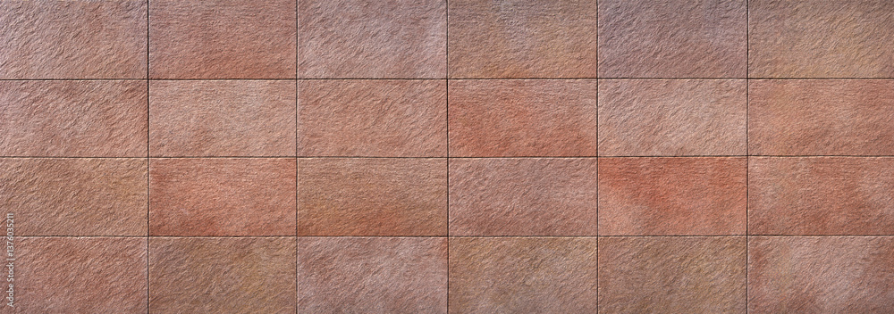 Fototapeta premium Wandverkleidung aus großen rotbraunen rechteckigen Steinplatten - Panorama einer Fassade