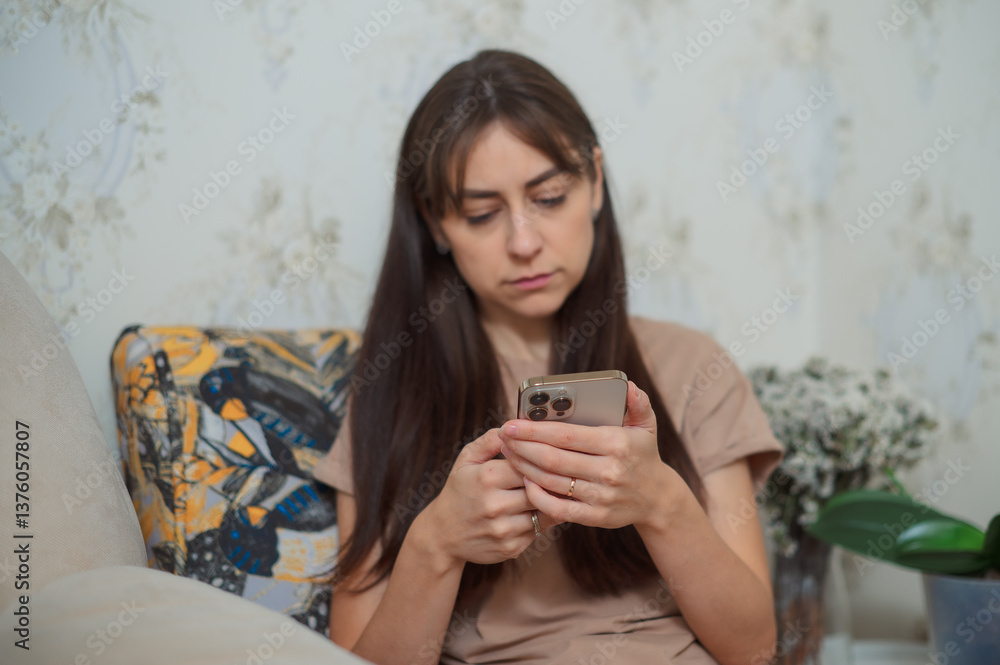 Young woman relaxing on cozy armchair, scrolling mobile smartphone screen during leisure time at home living room Young woman relaxing on cozy armchair, scrolling mobile smartphone screen during leisure time at home living room