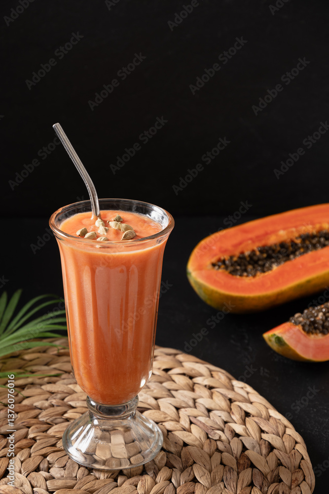 Asian traditional papaya lassi on dark background. Freshness cold beverage of yogurt, water, spices, fruits and ice. Popular beverage in India and Sri lanka. Vertical format.