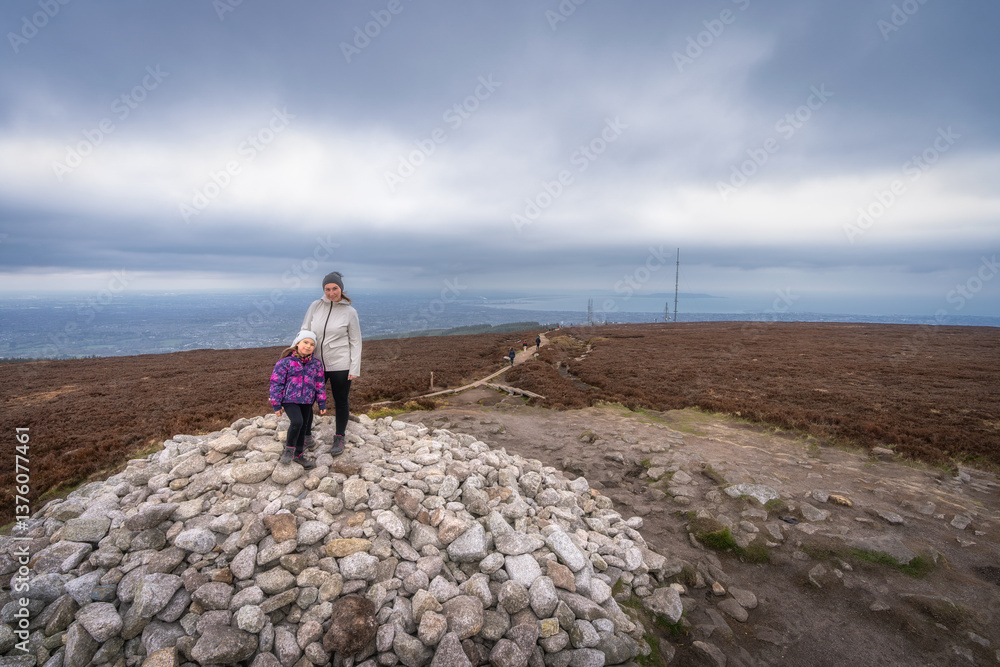 A family embarks on a thrilling exploration of a rocky summit, creating lasting memories amidst the breathtaking dramatic skies and expansive views they encounter, Wicklow, Dublin, Ireland