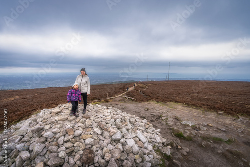 Obraz na płótnie A family embarks on a thrilling exploration of a rocky summit, creating lasting memories amidst the breathtaking dramatic skies and expansive views they encounter, Wicklow, Dublin, Ireland w salonie