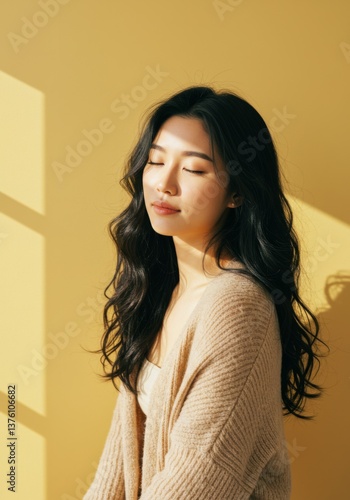 Serene woman relaxing in sunlit room with yellow background