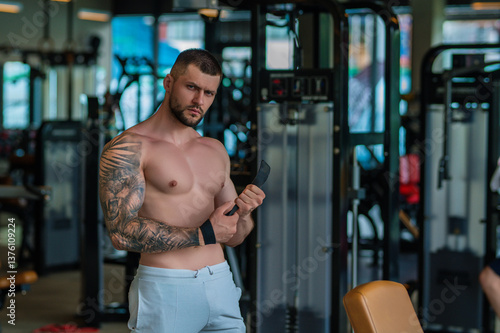 Obraz na płótnie Fit guy doing exercise at gym. Handsome sporty man workout with with dumbbells on gym. Male athlete with dumbbell on fitness workout. Fitness man in gym. Muscular sportsman workout with weight in gym. w salonie