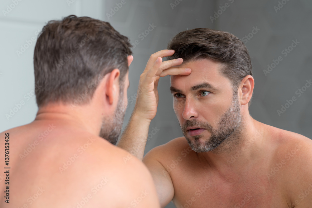 Obraz premium Male beauty cosmetics, beauty and skincare. Morning healthcare and hygiene for man. Perfect beauty skin. Handsome millennial man after shower apply nourishing facial cream or mask on skin.
