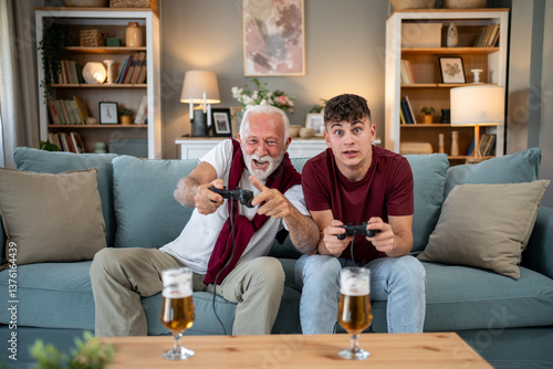 Fotografi Grandfather and grandson playing video games with beer on the table