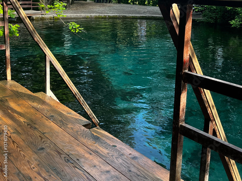 A wooden staircase descends into a turquoise-transparent lake. An organized place for swimming , entrance to the water in the form of steps