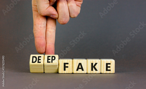 Deepfake or fake symbol. Concept words Fake Deepfake on wooden cubes. Beautiful grey table grey background. Businessman hand. Business and deepfake or fake concept. Copy space.