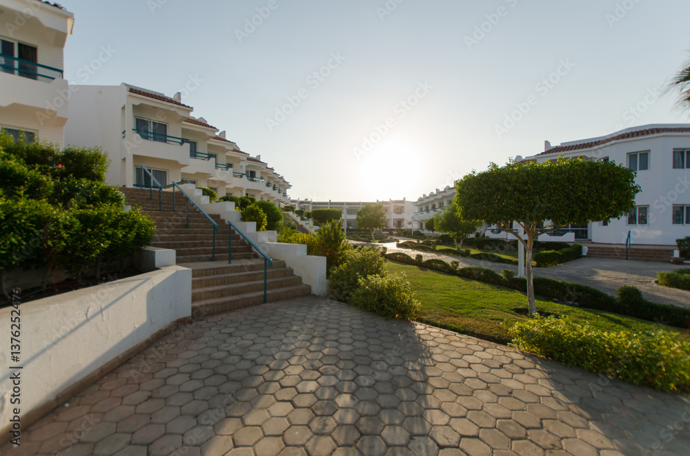 Fototapeta premium Scenic resort pathway at sunset with lush greenery