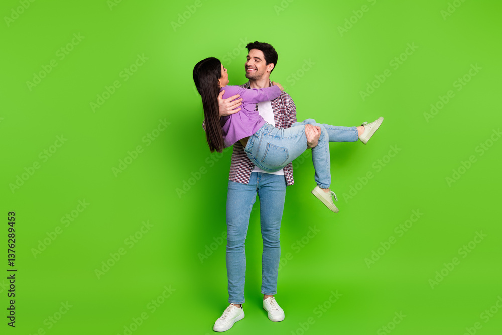 Young couple in casual attire enjoying a playful moment against a bright green backdrop Young couple in casual attire enjoying a playful moment against a bright green backdrop