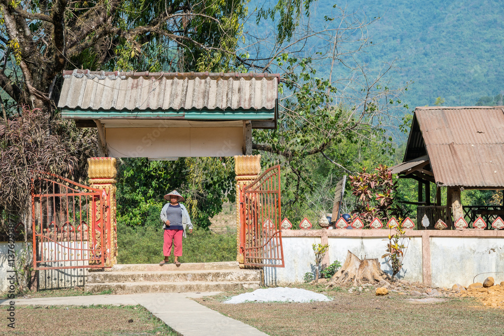 Obraz premium Laos, the Serene Countryside Adorned with Charming Rustic Huts and Majestic Mountain Backdrop