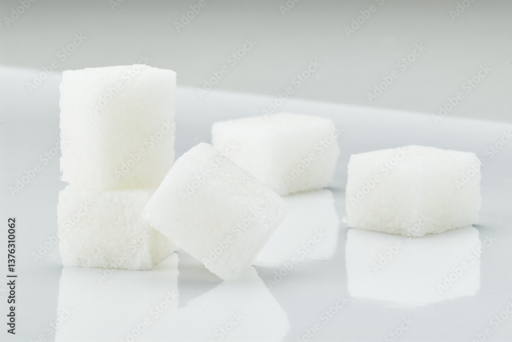 Arrangement of white sugar cubes on a glossy surface, showing their texture and simplicity. Arrangement of white sugar cubes on a glossy surface, showing their texture and simplicity.