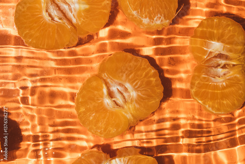 Peeled fresh mandarin halves in water, splash water, top view