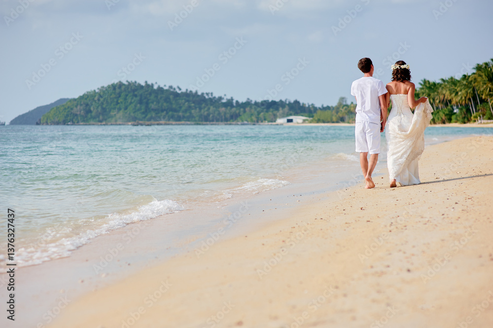 Newlywed Couple Strolls on a Serene Beach with Island Backdrop Newlywed Couple Strolls on a Serene Beach with Island Backdrop